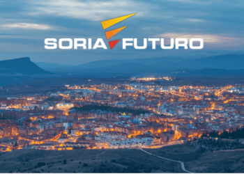 Soria ciudad con iluminación nocturna y paisaje montañoso en el horizonte.