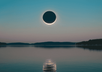 Eclipse solar total sobre el embalse de Soria, con reflejo en el agua y cielo despejado.