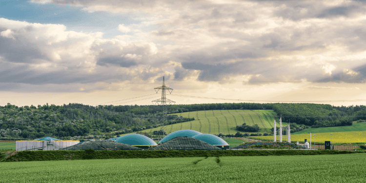 Planta de biometano en Soria con campos verdes y cielo nublado.