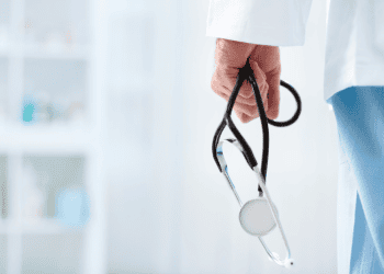 Médico con estetoscopio en mano en un entorno clínico.