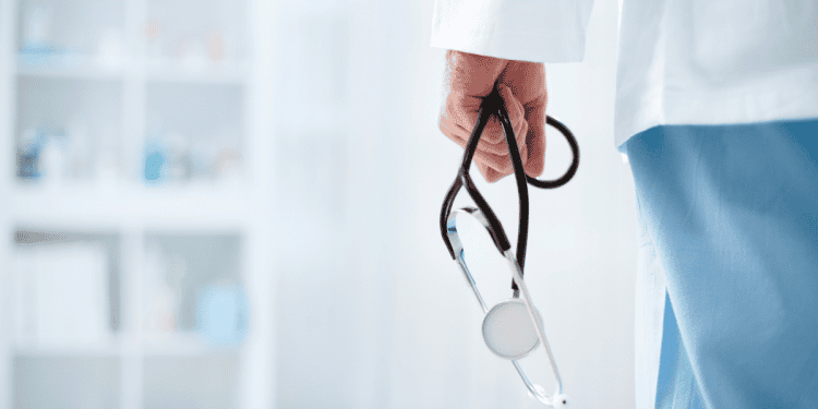 Médico con estetoscopio en mano en un entorno clínico.