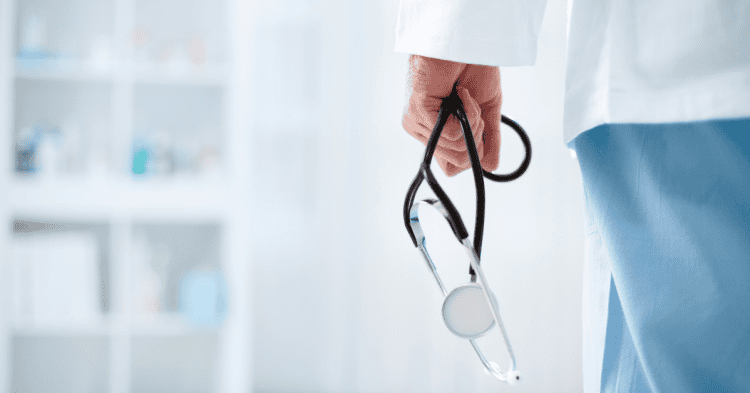Médico con estetoscopio en mano en un entorno clínico.
