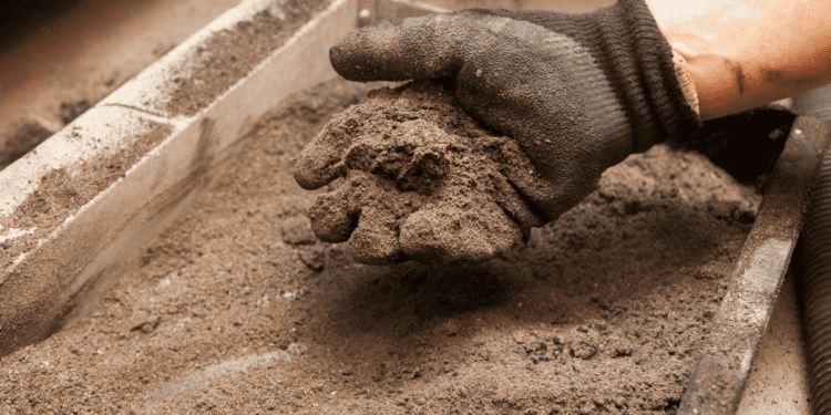 Mano con guante colocando cemento en una estructura de construcción en Soria.
