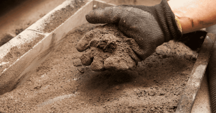 Mano con guante colocando cemento en una estructura de construcción en Soria.