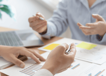 Reunión de negocios con análisis de datos y gráficos en oficina moderna.