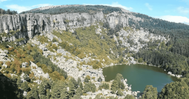 Lago rodeado de riscos y bosque en La Laguna Negra, paisaje de Castilla y León.