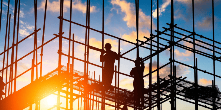 Trabajadores de una estructura de acero en construcción durante atardecer.
