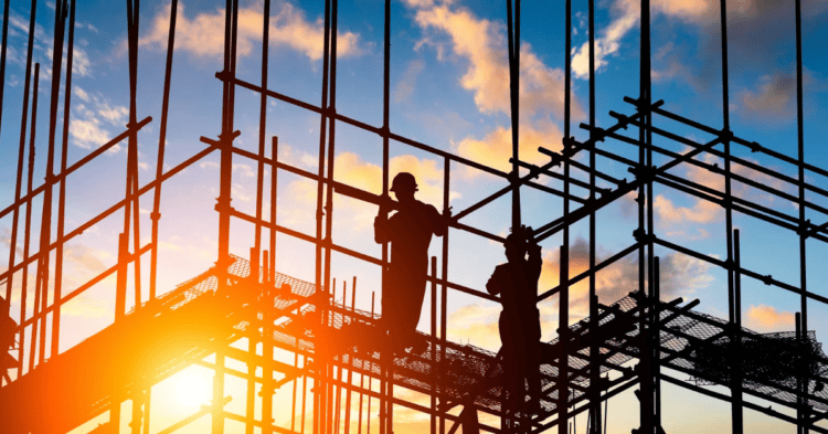 Trabajadores de una estructura de acero en construcción durante atardecer.